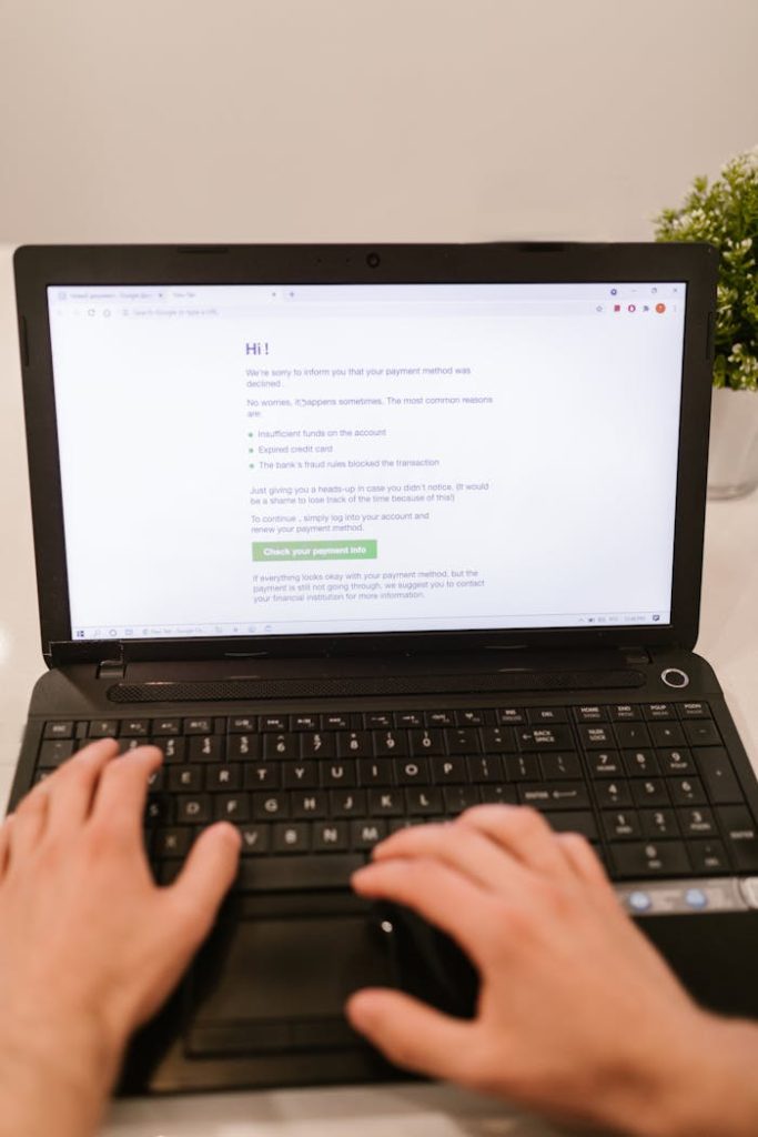 Close-up of hands typing on laptop keyboard, focusing on online payment verification.